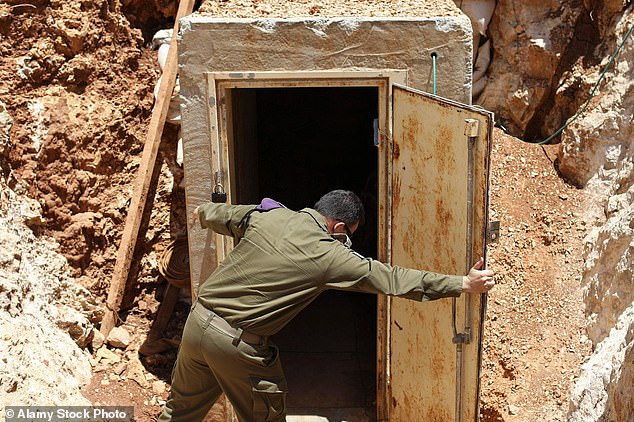 An Israeli army soldier holds the entrance door to a tunnel dug by the Lebanese Islamist political party and militant group Hezbollah.