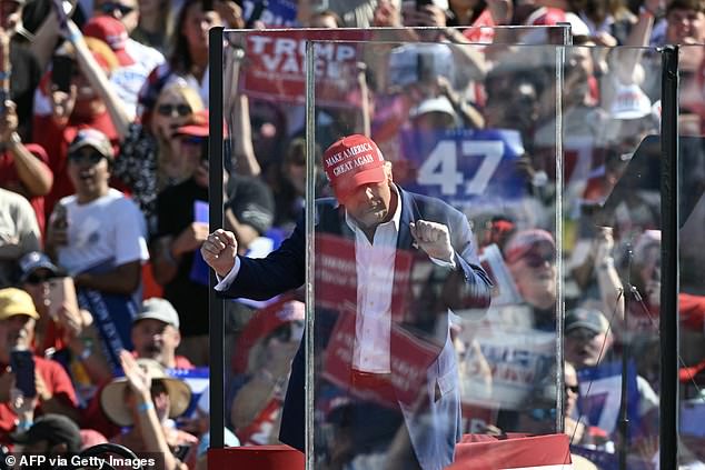 Former US President and Republican presidential candidate Donald Trump dances behind bulletproof glass as he concludes his remarks during a campaign rally at the Aero Center in Wilmington, North Carolina, on September 21, 2024.