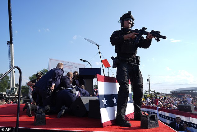 Republican presidential candidate, former President Donald Trump, is covered by US Secret Service agents.