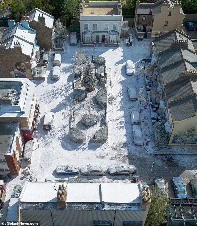 A large Christmas tree was placed in the middle of the square that was covered in snow and several red and gold Christmas boxes were placed underneath.