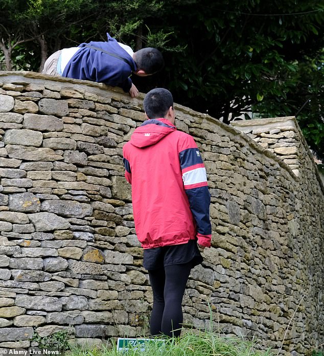 The visitor was seen climbing up a stone wall towards his friend.