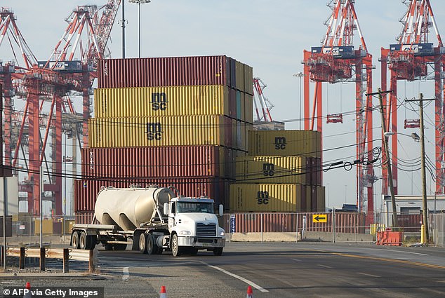 A truck passes shipping containers at Port Newark in New Jersey. Port workers will return to work after the union and port operators reached a tentative agreement on wages and extended the current contract until January 15.