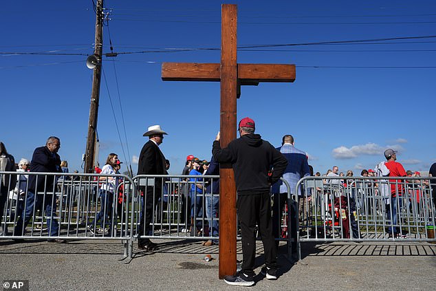 Dan Beasley of Northville, Michigan, holds a cross as Republican presidential candidate, former President Donald Trump, speaks at a campaign rally at the Butler Farm Show.