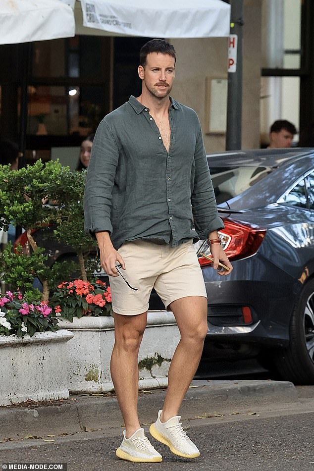 James dressed casually in a green button-down shirt, beige shorts, and a pair of sneakers.