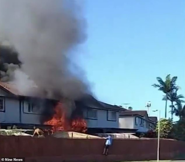 Neighbors rushed to the scene, jumping the fence and running towards the burning house (pictured).