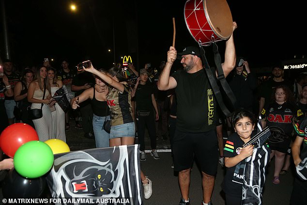 Flags, balloons, replica jerseys, Penrith Panthers jerseys and a man with a drum.