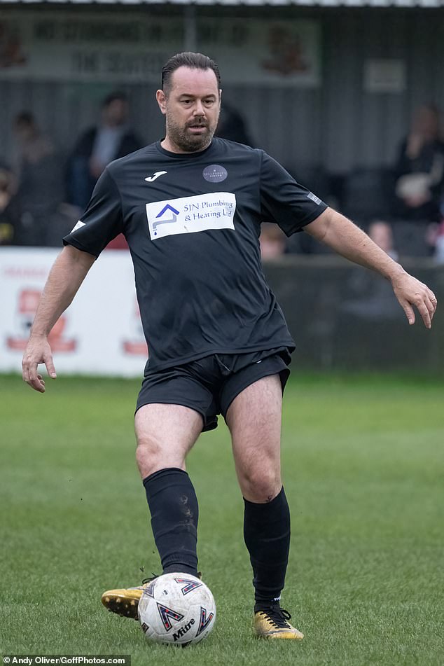 Danny cut a sporty figure in a black sports shirt and shorts, while protecting his legs with some shin guards.