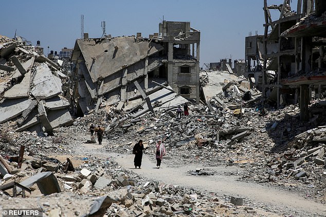 Palestinians walk past the rubble of houses destroyed during the Israeli military offensive, amid the conflict between Israel and Hamas, in Khan Younis, southern Gaza Strip, on July 10, 2024.