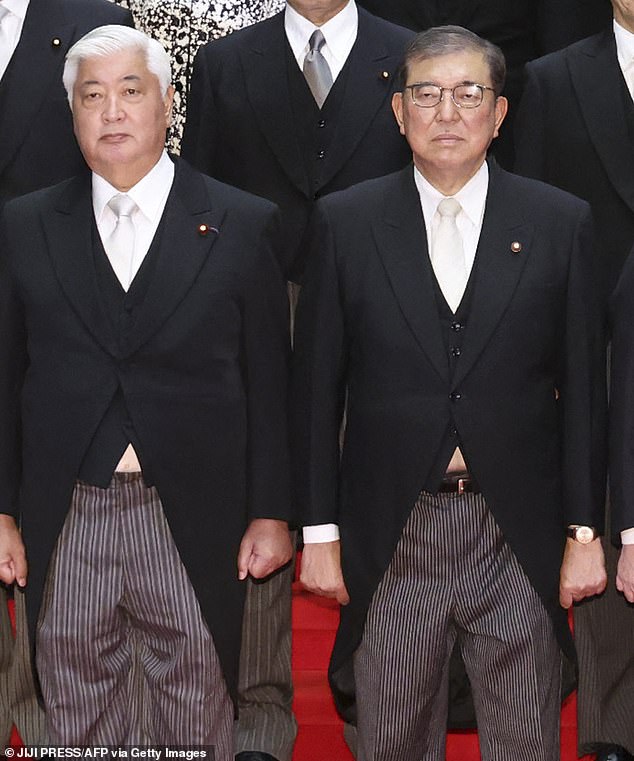 In the original unedited images, which appeared in local media publications, small patches of white shirts can be seen peeking out from under the suits of the Prime Minister (right) and the Japanese Defense Minister (left).