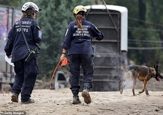 Members of FEMA's Urban Search and Rescue Task Force search a flood-damaged area with a search canine following Hurricane Helene along the Swannanoa River on October 4, 2024 in Asheville, North Carolina.