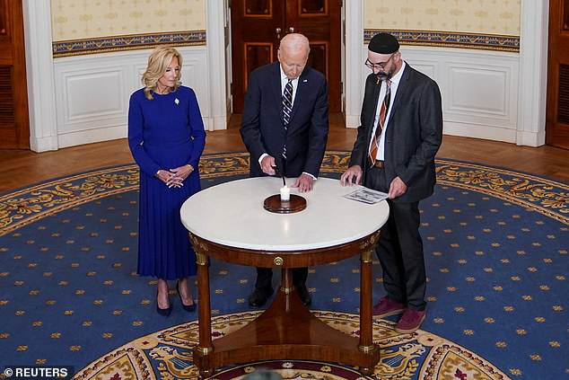 US President Joe Biden, flanked by First Lady Jill Biden and Rabbi Aaron Alexander of Congregation Adas Israel, lights a candle to mark the anniversary of the October 7 Hamas attacks.