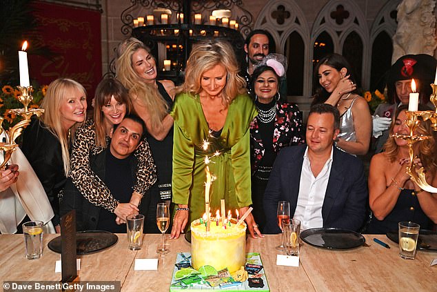 The socialite, who wore a green satin cape dress for the occasion, looked delighted as she blew out the candles on her cake surrounded by her loved ones.