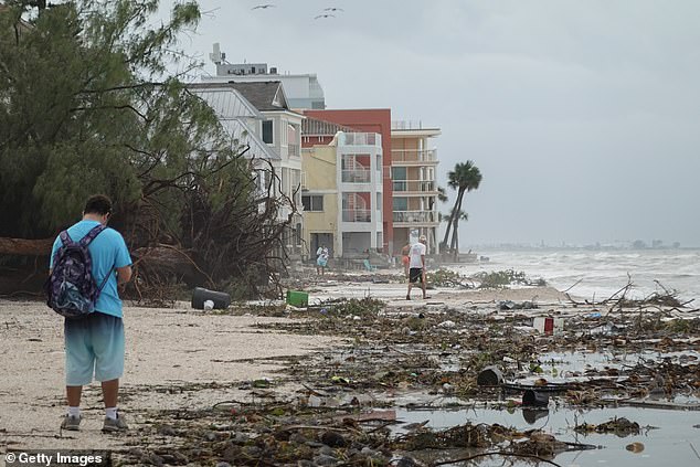 Trees and debris lay on the beach at Treasure Island as people walked after Helene's landing.