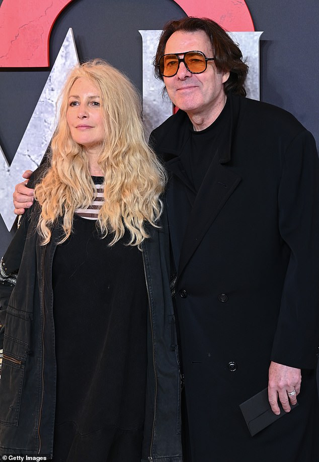 Jonathan wore a stylish black coat and orange glasses as he sweetly put his arm around his wife.