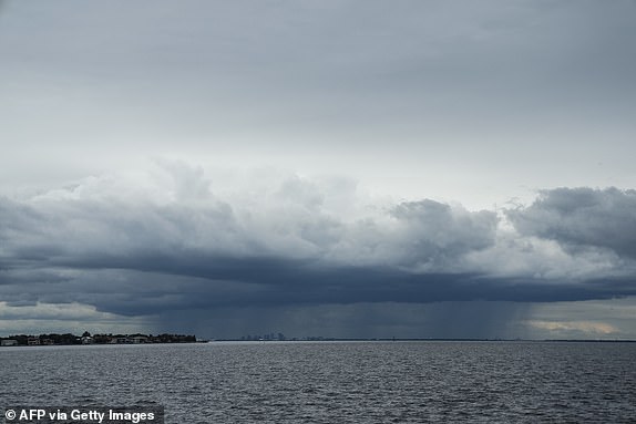 TOPSHOT - A storm can be seen moving over Tampa in the distance from St. Petersburg, Florida, ahead of Hurricane Milton's expected arrival in the middle of this week on Oct. 8, 2024. Storm-hit Florida braced Tuesday for a direct hit from Hurricane Milton. , a monster weather system that threatens catastrophic damage and forces President Joe Biden to postpone a major trip abroad. (Photo by Bryan R. SMITH/AFP) (Photo by BRYAN R. SMITH/AFP via Getty Images)