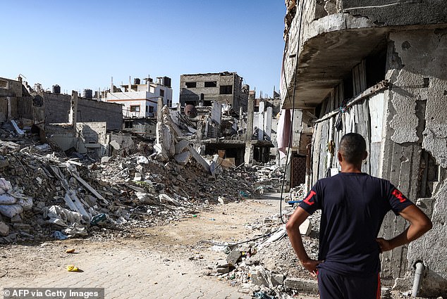 A man stands in front of a collapsed building in the Bureij camp for Palestinian refugees in the central Gaza Strip on October 9.