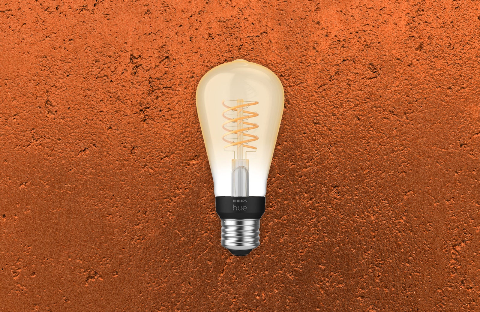 Yellow-dyed bulb with spiral filament inside. Dimpled bronze texture background.