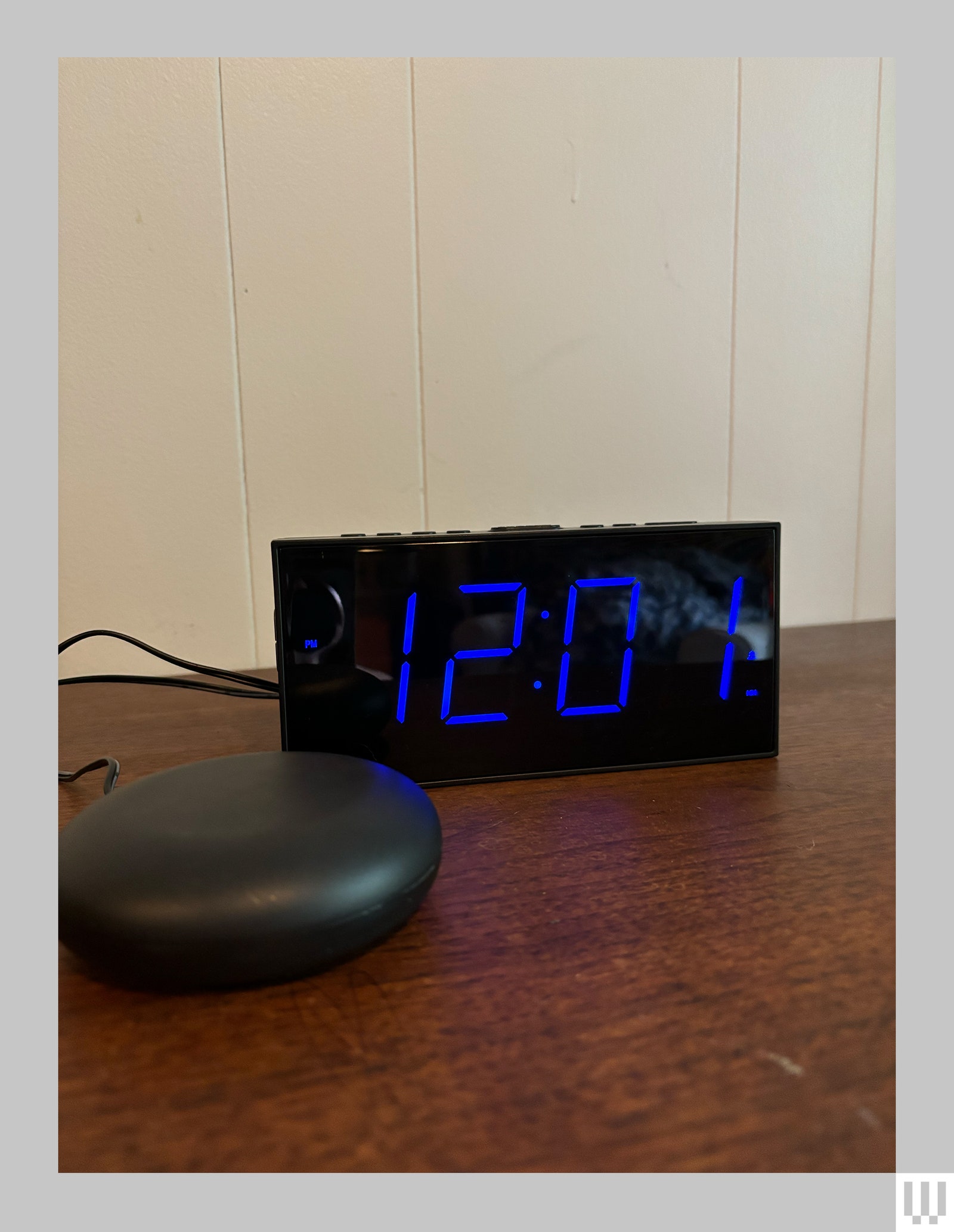 Rectangular alarm clock on a wooden surface and connected to a vibrating device