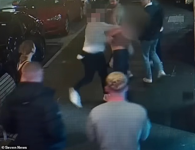 The Brisbane Lions fan (pictured center) pulls his arm back before slamming his fist into Poppy's jaw, sending the young tourist flying backwards into a wall.