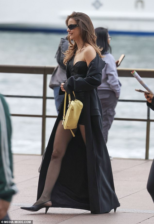 She also wore a glamorous long black coat and accessorized it with a yellow Versace bag worth $2,200.