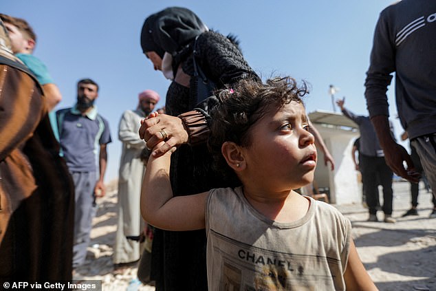 A woman holds the hand of a child as Syrians who were refugees in Lebanon return to their home country after a trip to the opposition-held northern province of Idlib, via the Aoun al-Dadat crossing, to north of Manbij, on October 9, 2024.