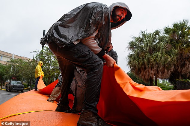 As Tampa prepares for the arrival of Hurricane Milton, workers help the National Guard place a flood barrier around a wastewater facility in the city.