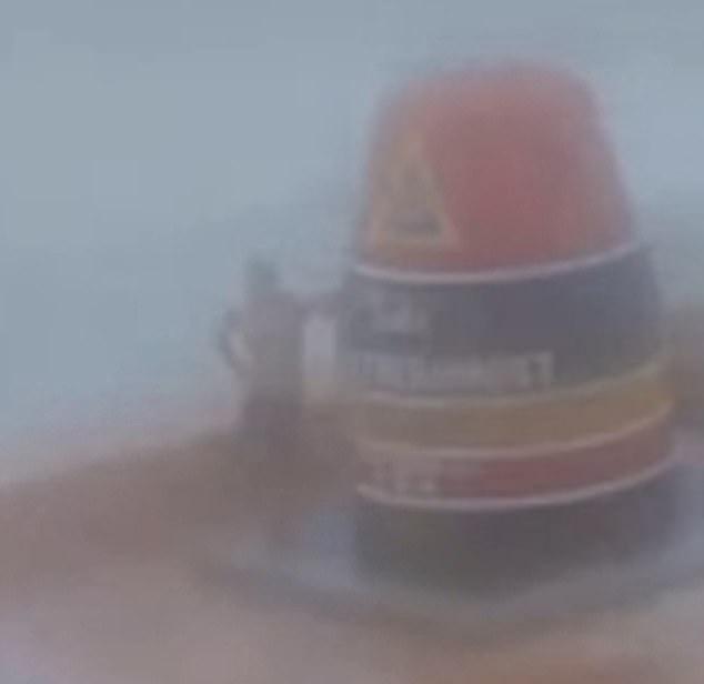 A man poses for a photo with the Southernmost Point buoy in Key West as the iconic landmark was battered by rain and high winds Wednesday.