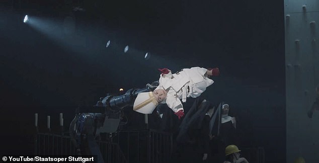 At one point, an actress with dwarfism is dressed as the Pope is lifted into the air and rotated by a robotic arm.