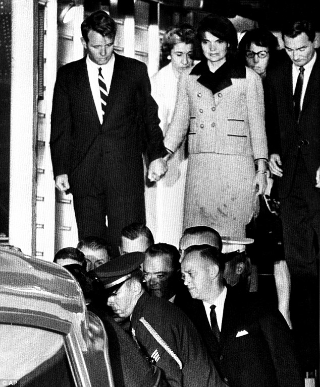 Jackie Kennedy grabs Bobby's hand as she stands in her blood-stained clothes as the casket carrying President John F. Kennedy's body is placed into an ambulance after arriving at Andrews Air Force Base.