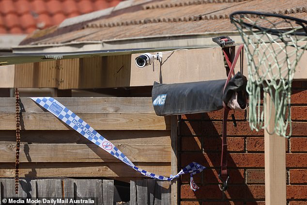 Police tape is seen on the back fence of the property.