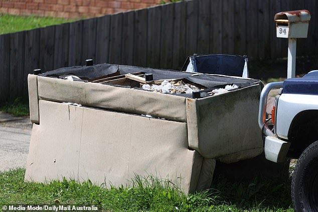 An upturned sofa is seen in the front of the house.