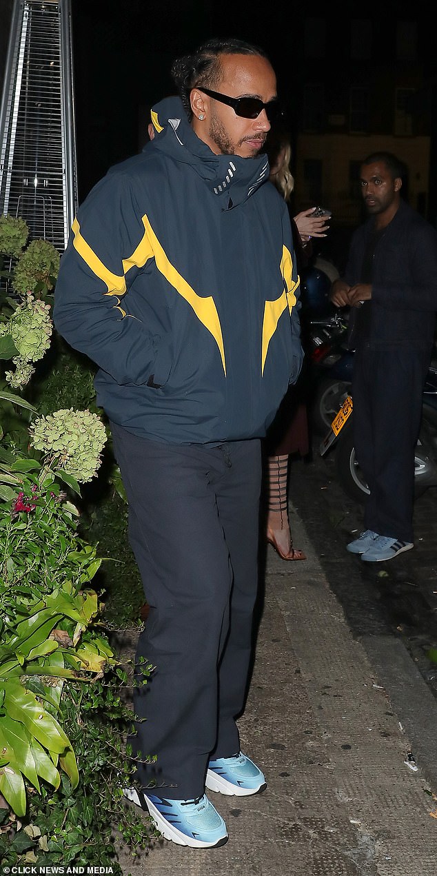 Lewis cut a modern figure in a black and yellow jacket and matching pants, completing the look with blue sneakers and rectangular sunglasses.