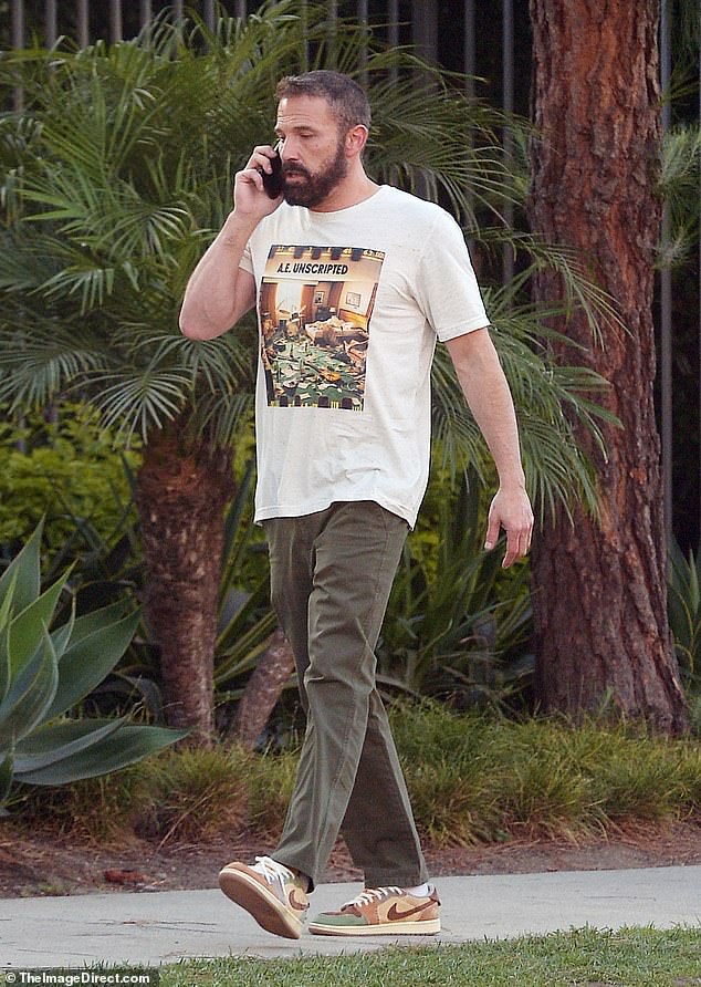 He looked casual in a white graphic T-shirt, skinny olive pants, and a trendy pair of green and brown Nike sneakers.