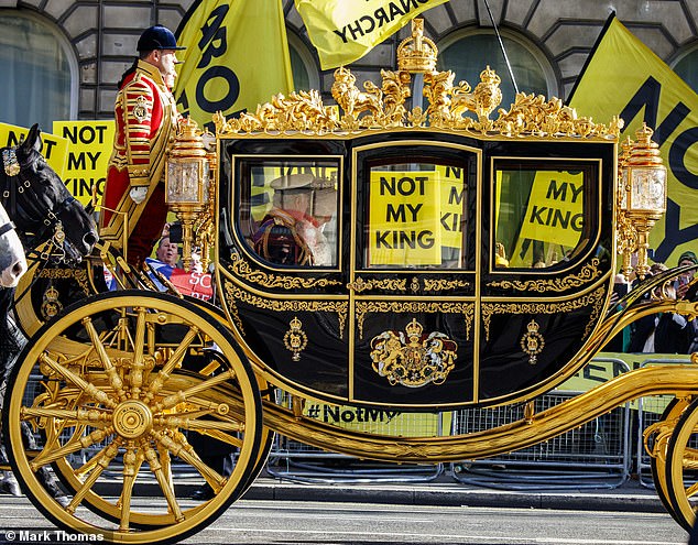 Charles III and Queen Camilla pass by a group of anti-royalists with signs of 