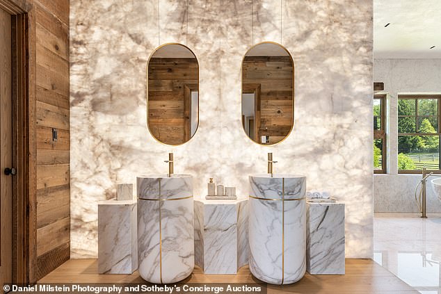 A backlit white quartz vanity with his and her sinks can be seen in one of the bathrooms.