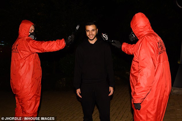 In another snap, Junior smiled as he posed for the camera alongside two men in red protective suits and face coverings.