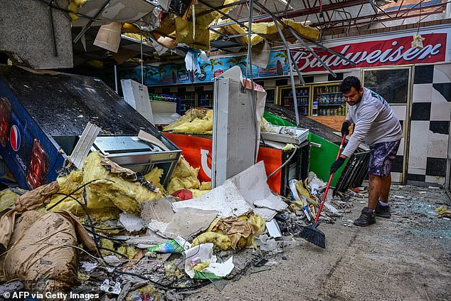 A man cleans debris inside a gas station in Lakewood Park, Florida, after Hurricane Milton.