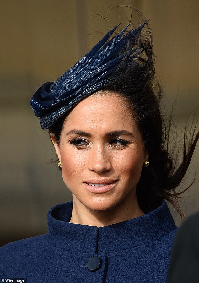 Meghan wearing a navy coat and matching headpiece at Eugenie's wedding in 2018