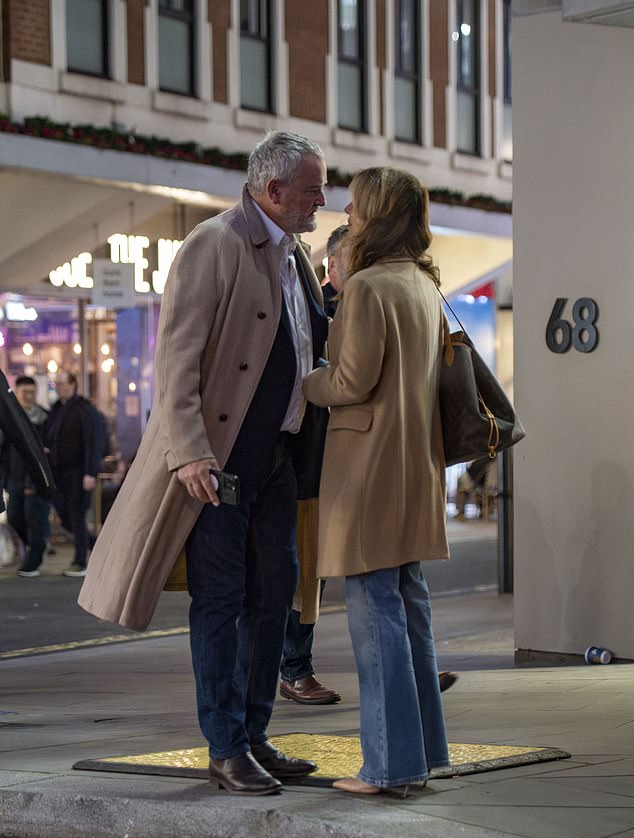 Hugh put on a long wool coat and put an arm around his girlfriend as they strolled through the city.