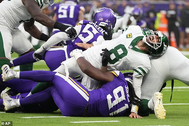 New York Jets quarterback Aaron Rodgers (8), right, reacts when he is tackled during the second half of an NFL football game against the Minnesota Vikings.