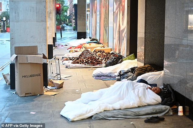 Pictured: Rough sleepers lie in their makeshift beds outside closed shops, at dawn on Oxford Street in London on August 2, 2023.