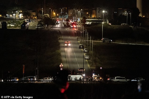 Israeli security forces and first responders gather at the site of a drone strike as an ambulance passes by.