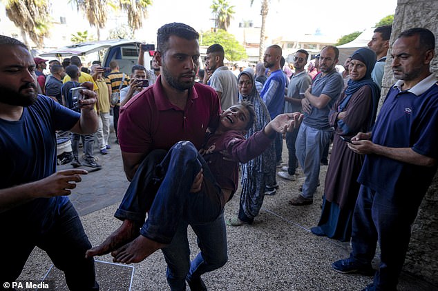 A Palestinian carries an injured child after an Israeli airstrike in Deir al Balah