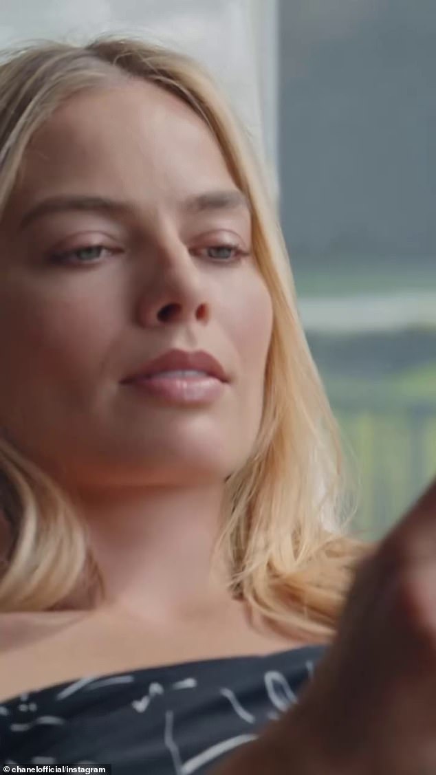 The commercial, directed by Luca Guadagnino, begins with Margot looking as glamorous as ever in a black dress as she sits in a window seat and checks her phone.