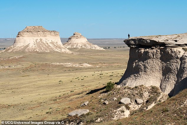 A person looks out over the Pawnee Buttes, which are made of crumbling sandstone.