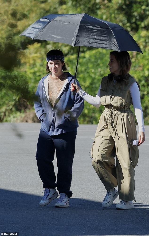 She covered her famous curves in a brown shirt, blue hoodie and sweatpants and wore minimal makeup as she was escorted to set.