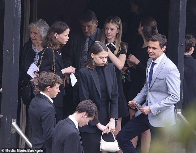 Lucía, also dressed in black, is seen holding a white bag and maintaining a serene expression, although the weight of the day's sadness is clear in her behavior.