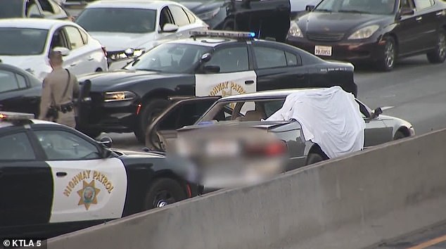 A white sheet is seen thrown over the car after the deadly shooting.