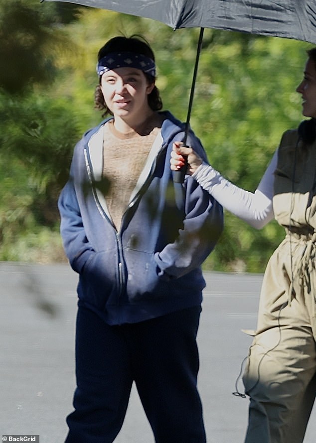 The star, known for her blowout blonde look and famous curves, completed the transformation with a curly brown wig and white and gray sneakers.