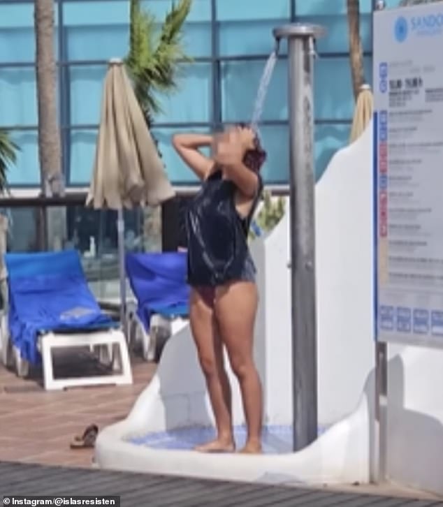 A woman is seen showering by the hotel pool as Lanzarote residents struggle with water outages.